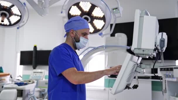 マスクの統一医師は肺換気機械のセンサー スクリーンのキーを押します 手術のために準備する機器のパラメータを選択する医療専門家 — ストック動画
