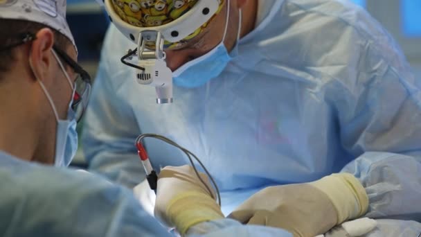 手術外科医は ツールを使用して患者の上に低く曲がった 医師は頭のフラッシュライトでハイライトする繊細な作業を行います — ストック動画