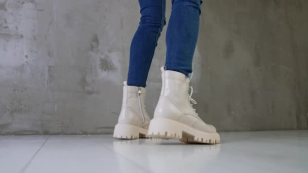 白い革の軍隊がジーンズを着ている女性をブーツします スタジオでスタイリッシュな靴を披露する女性 — ストック動画