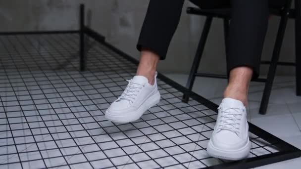 Nowoczesne Wygodne Białe Buty Sportowe Mężczyzna Model Siedzi Krzesło Utrzymując — Wideo stockowe
