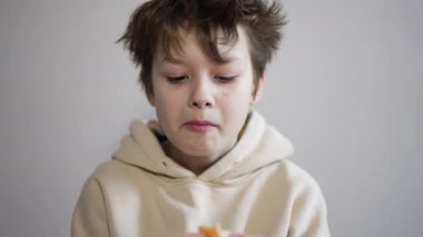 On üç yaşında mandalina yiyen bir genç. Çocuk bir meyveyi çiğnerken parça parça alıyor. Kapat..