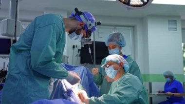 Modern operasyon odasında ameliyat yapan profesyoneller takımı. Hemşire doktorlar için hazırlanmış aletleri uzatıyor..
