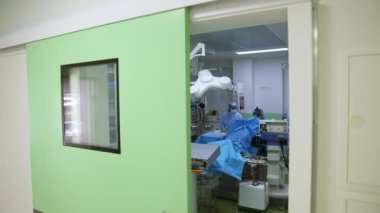 Modern, iyi donanımlı bir ameliyatta hemşireye asistanlık yapan tek çalışan bir cerrah. Çağdaş operasyonel tiyatronun kapılarına bakıyorum..