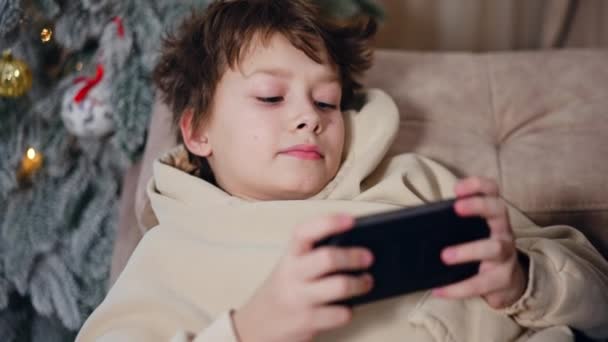 Rapaz Cabelos Escuros Deita Sofá Com Telefone Nas Mãos Kid — Vídeo de Stock