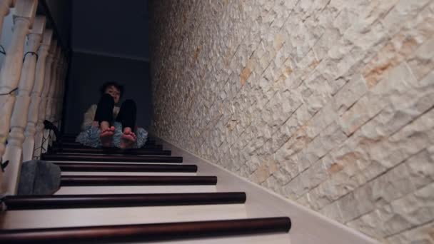 ピローの上の階段を滑ろうとしているあわてた少年 ティーンエイジャーは屋内でステップバイステップで降下柔らかいふわふわの枕に座っています — ストック動画