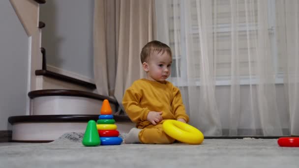 Αγοράκι Πορτοκαλί Κοστούμι Παίζει Μια Πυραμίδα Παιχνιδιών Στο Πάτωμα Του — Αρχείο Βίντεο