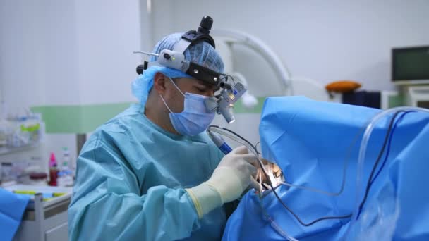 オトリガロジーオペレーションで革新的な機器とデバイスを使用した外科医 男性の医師は 運用エリアの特別な技術眼鏡を通して見ます — ストック動画
