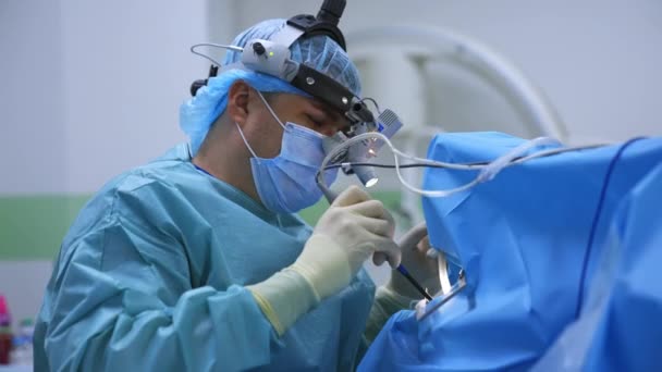 ナス外科医は 操作に使用するデバイスを調整します 手術中のデバイスメガネを搭載したオトリガロジスト — ストック動画