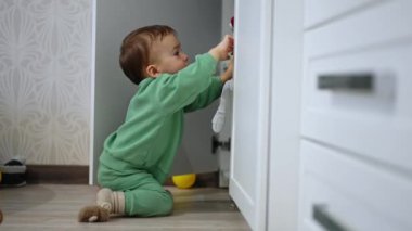 Şirin çocuk odadaki dolabın kapısını açıyor. Evi keşfeden meraklı bir bebek..