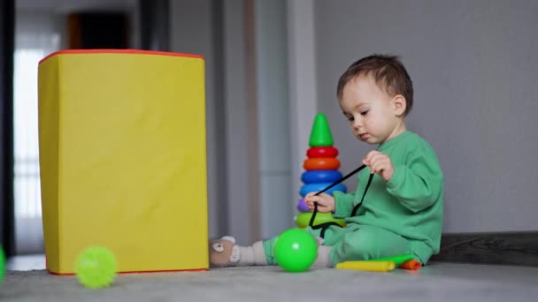 黄色いおもちゃ箱の床に座っている白人の赤ん坊 黒いレースで遊ぶ美しい子供 — ストック動画