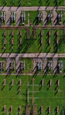 Güç iletim hatları. Yeşil alan arka planında yüksek voltajlı sütunların üzerinden uçmak. Hava görüntüsü. Dikey video