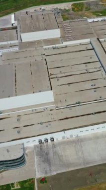 Yeşil alanda endüstriyel fabrika. Araba parkı olan modern üretim. Yol kenarında bir sürü binası olan büyük bir sanayi bölgesi. Hava görünümü Dikey video