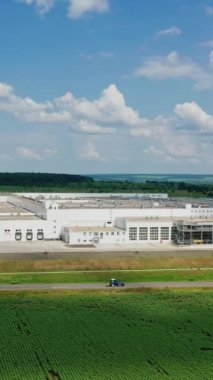 Yeşil alanda modern endüstriyel kompleks. Yolun yakınındaki geniş bir üretim bölgesi ve güzel doğa geçmişi olan arabalar. İHA görüntüsü. Dikey video