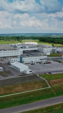 Doğanın sanayi kompleksi. Güzel yeşil manzarada modern imalat. Hava görüntüsü. Hareket kamerası geri. Dikey video