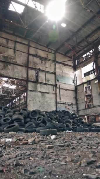 大的老工厂 里面有垃圾和一堆旧橡胶轮胎 已经不适合在受损工厂的车辆上使用的轮胎 垂直录像 — 图库视频影像