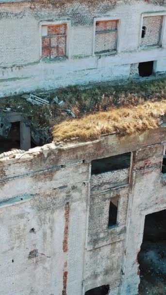 ドアや窓なしで放棄された建物の外観の前面 軍事行動の後に荒廃した植物 空からの眺め バーティカルビデオ — ストック動画