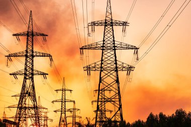 Yüksek voltaj kuleleri ve kırmızı gökyüzü ile elektrik hatları