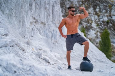 Genç atletik adam, beyaz dağların arka planında spor yaparak antrenman yapıyor.