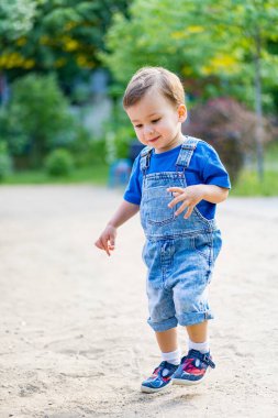 Küçük çocuk güneşli bir günde parkta kırmızı oyuncak arabasıyla oynuyor..