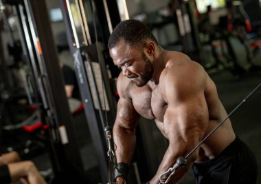 Spor salonunda kablo çapraz egzersizi yapan kaslı adam.