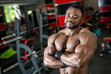 Spor salonunda dambıllarla poz veren kaslı Afrikalı Amerikalı adamın portresi.
