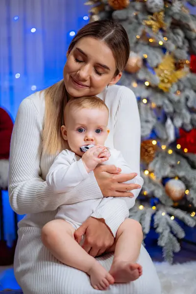 Mladá Matka Drží Své Dítě Náručí Líbá Tvář Vánoční Stromeček — Stock fotografie
