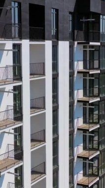 Şehirde yeni bir mimari. Yolun yakınındaki yüksek katlı apartmanlar. Çok katlı binanın modern tasarımı. İHA uçuşu. Dikey video