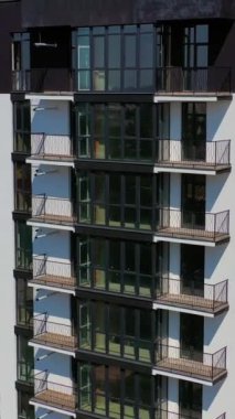 Yeni apartman binaları cephesi. Şehirde siyah-beyaz çok katlı mimarinin modern tasarımı. Balkonları ve yüksek pencereleri olan çok güzel bir bina. Dikey video