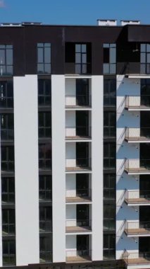 Şehrin banliyösünde yüksek katlı yeni bir bina. Yeni apartmanlar. Modern binaların videosu. Dikey video