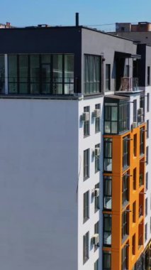 Şehirde çağdaş konut binası. Çok katlı bir apartmanın modern tasarımının dış cephesi. Hava görüntüsü. Dikey video