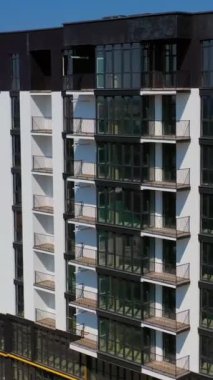 Şehirde yeni bir mimari. Güneşli bir günde apartmanın lüks tasarımı. Balkonlu, siyah beyaz bir apartman dairesi. Dikey video