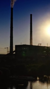 Endüstriyel fabrikanın karanlık silueti. Akşamları pipodan kirli duman çıkıyor. Doğada zararlı üretim. Kamera yükseliyor. Dikey video