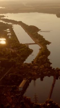 Akşam kırsal manzarası. Gün batımında geniş ırmağın panoramik manzarası. Kırsal kesimde doğanın akşam arkaplanı. Hava görüntüsü. Dikey video