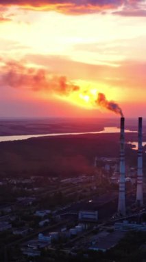 Endüstriyel fabrikanın kimyasal dumanlı boruları. Fabrikanın panoramik manzarası akşamları güzel doğayla çevrilidir. Hava kirliliği. Hava görüntüsü. Dikey video
