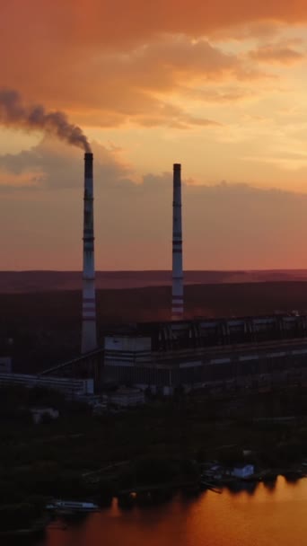日落时在河边工厂 工业厂房 烟斗在黄昏的天空中 生态问题 移动摄像头回来了 空中风景 垂直录像 — 图库视频影像