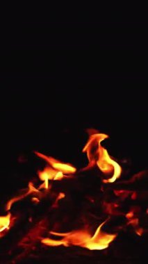 Kameraya uzanan ateşli dillere bakıyorum. Tepeden kamp ateşinin yakın görüntüsü. Dikey video