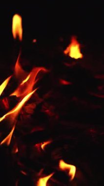 Rüzgarda savrulan büyük şenlik ateşinin tepesinde. Geceleri yanan alevi yakından izle. Dikey video