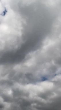 Kalın kümülüs bulutları gökyüzünde toplanıyor. Hızlı bulut dönüşümü zaman aşımı. Düşük açı. Dikey video