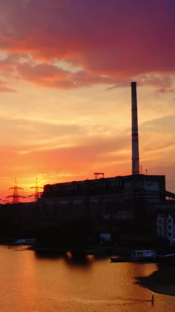 日没のピンクの空に対する有害な工場 産業煙突からの煙は環境を汚染する 夕方の川の近くにある化学プラント バーティカルビデオ — ストック動画