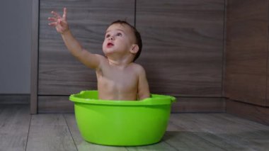 Banyo yapan sevimli çocuk bir şey için elini kaldırıyor. Güzel bebek lavaboda banyo yapıyor..