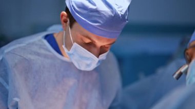 Maskeli iki erkek doktor ameliyat edilen hastaya doğru eğildi. Cerrahlar ameliyatta. Kapatın. Bulanık arkaplan.