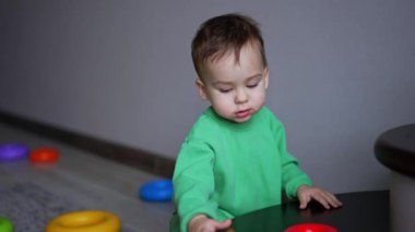 Sevimli beyaz çocuk, önünde yatan emziği alır. Tatlı çocuk etrafa saçılmış oyuncağa bakıyor..