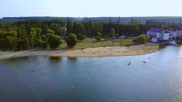 川の川が街に流れている 砂と緑の木とそこに休んでいる人々と美しい絵のようなビーチ エアリアルビュー — ストック動画