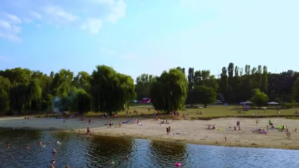 晴れた夏の日に川の美しい岸で休んでください 街の郊外で自然を楽しんでいる人 — ストック動画