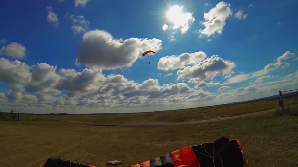 パラチューティストはゆっくりと空に降りて 柔らかく着陸する 背景に白い雲が付いている美しい青空 — ストック動画