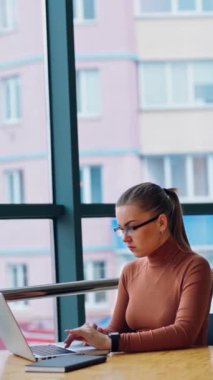 Bilgisayarda yazan odaklanmış kadın etrepreneur. Genç bir bayan evde otururken bilgisayar kullanıyor. Modern cihazlar üzerinde çalışan serbest çalışan meşgul bir işçi. Dikey video