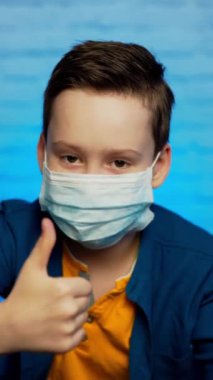 Koruyucu yüz maskesi takan bir çocuk. Coronavirus 'u koruma kavramı. Koronavirüsü durdurun. Evde kal Dikey video
