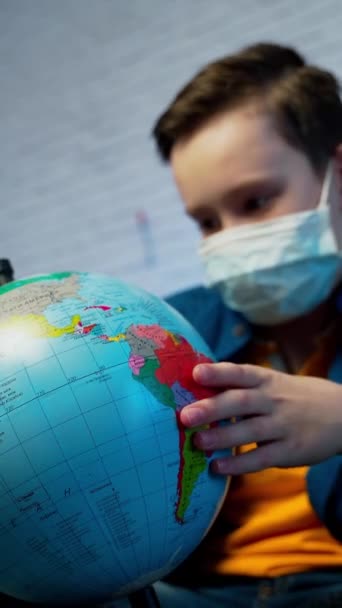 世界中でウイルスが広がっていることを知る少年 メディカルフェイスマスクを着用している少年 Covid 19パンデミック感染の概念 バーティカルビデオ — ストック動画