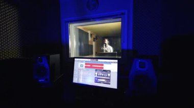 Müzik kaydı için modern ekipmanlı karanlık oda. Erkek şarkıcı mikrofonun önünde şarkı söylüyor..
