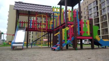 Kaydırak ve merdivenleri olan çocuklar için güzel, parlak bir oyun alanına yaklaşıyoruz. Ortası çocuk parkı olan bir yerleşim yeri. Düşük açı görünümü.